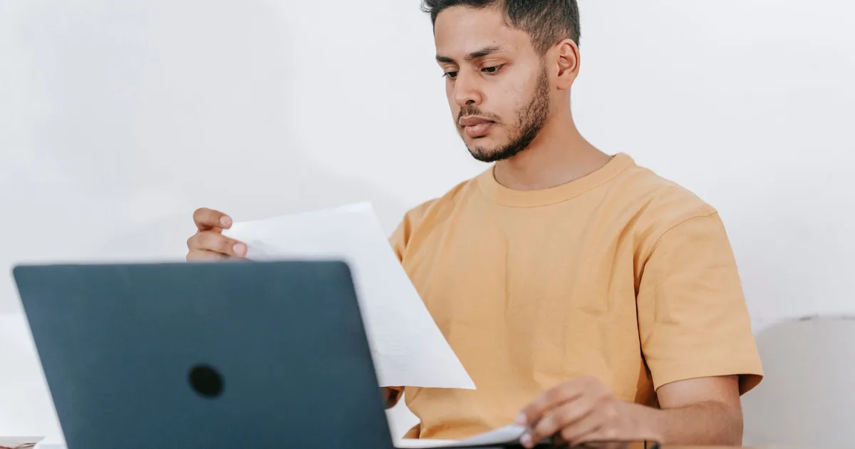 Free car history check: person reviewing used car paperwork on a laptop, checking DVLA records and MOT history before buying